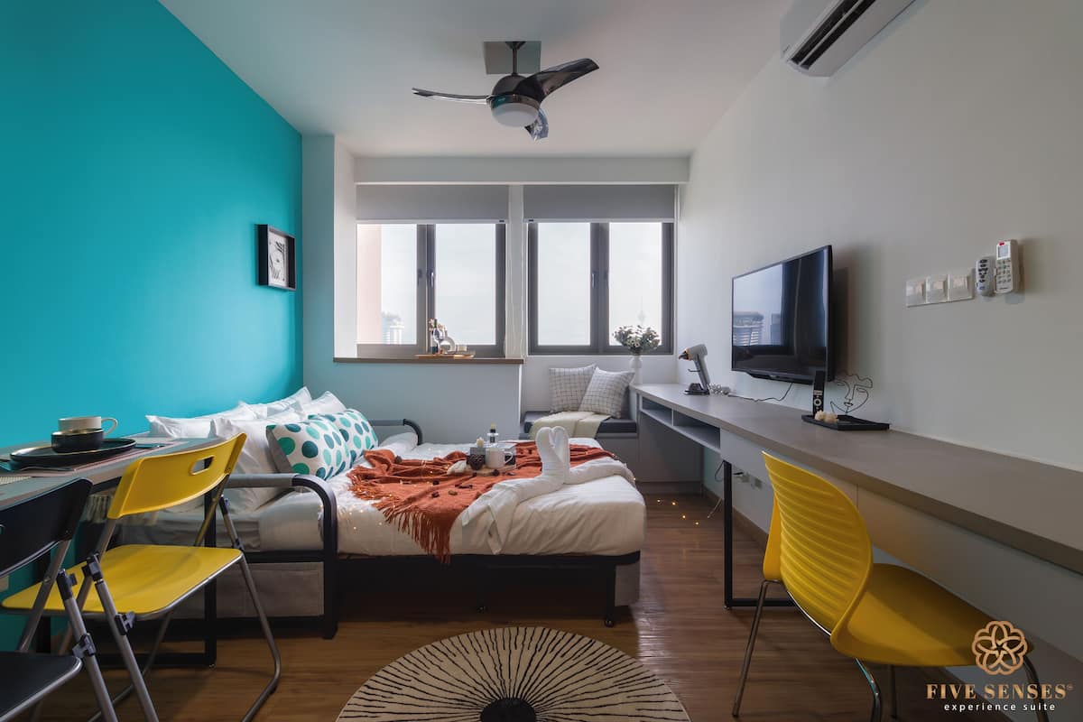 A modern bedroom with a bed, a desk, a chair, and a TV.
