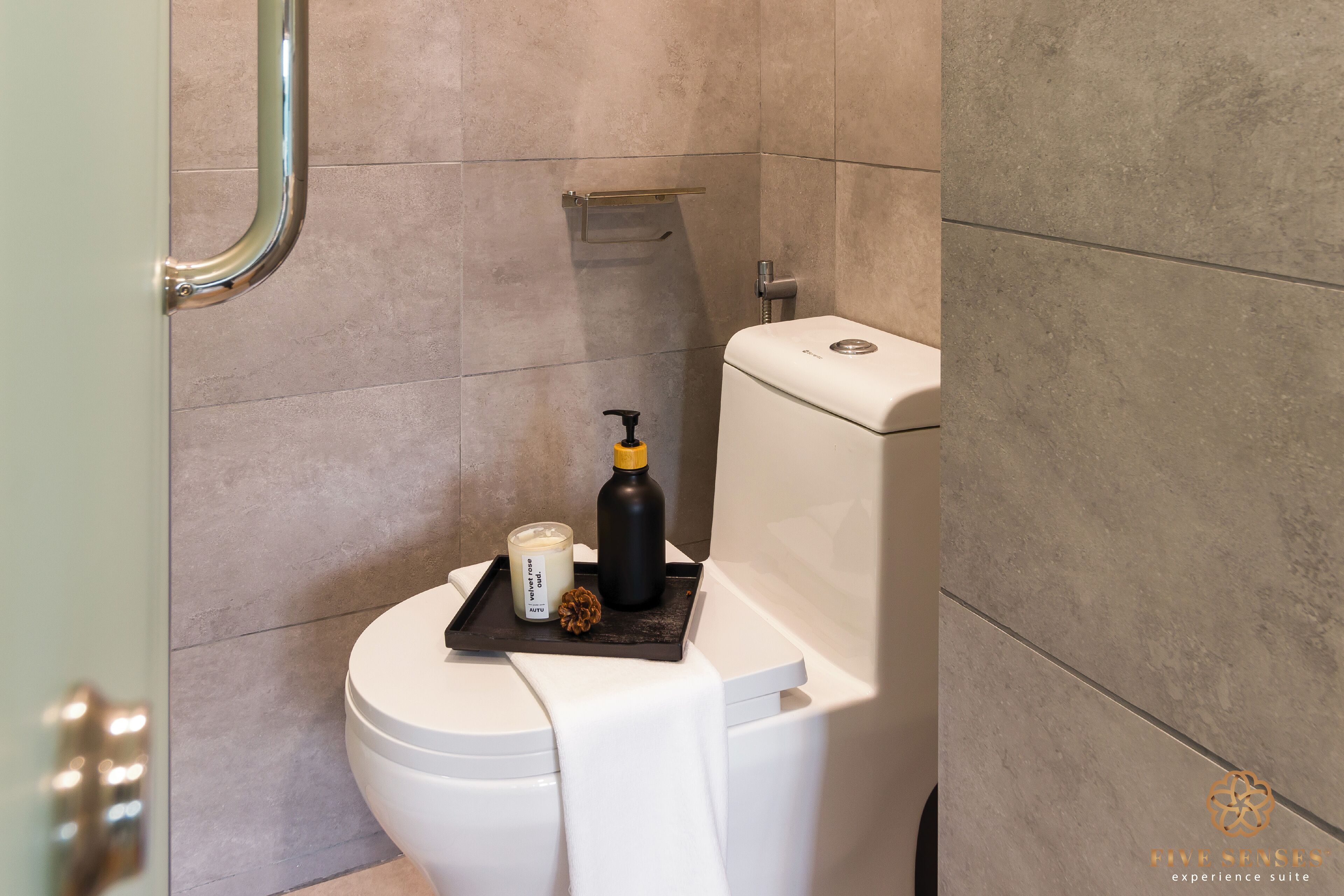 A modern bathroom with a toilet, a shower area, and a shelf with toiletries.