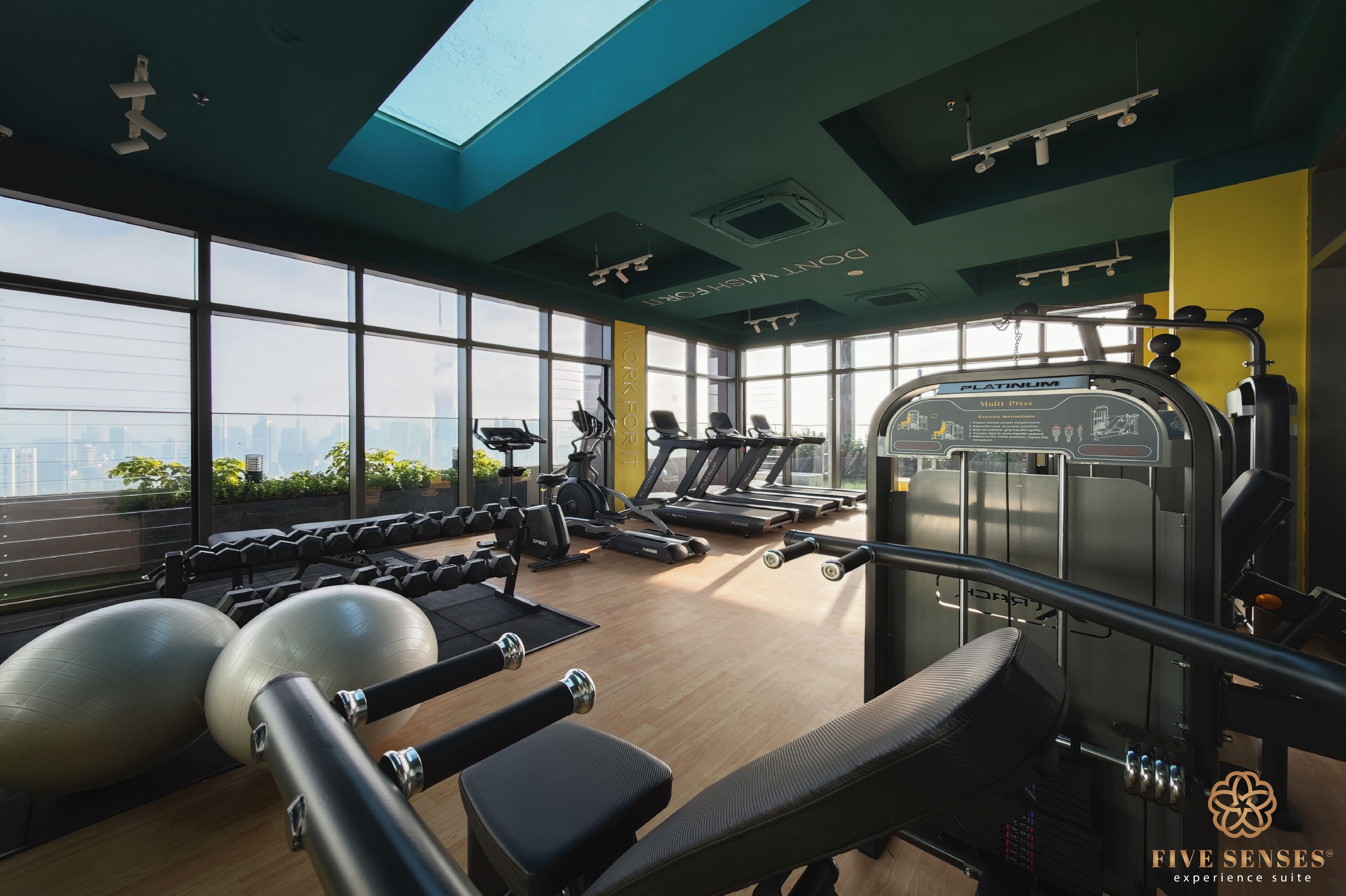 A gym with exercise equipment, large windows, and a view of the city.