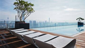 A rooftop pool area with lounge chairs and a city skyline view.