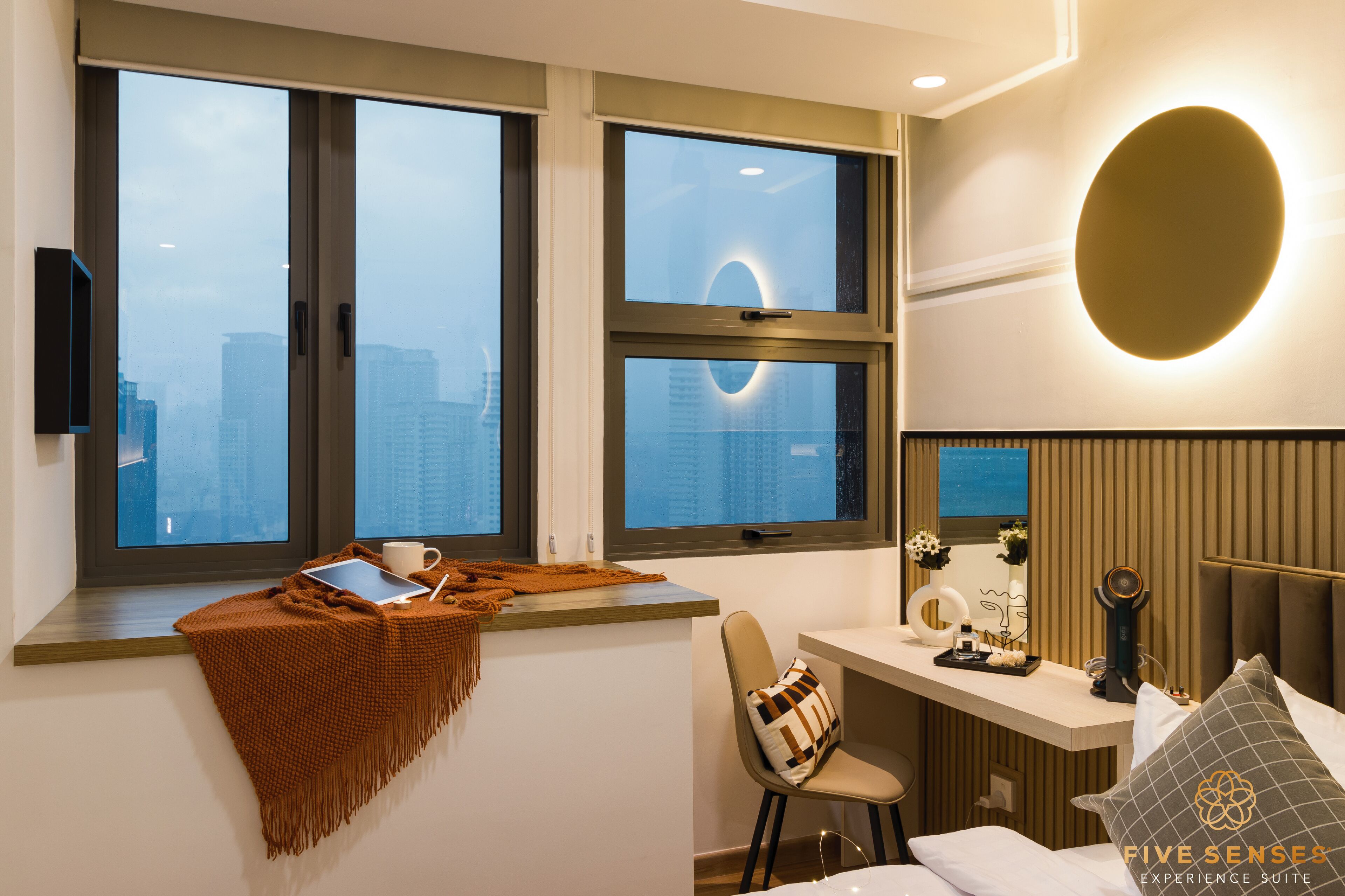 Une chambre d’hôtel moderne dotée de grandes fenêtres, d’un bureau avec un ordinateur portable, d’une chaise et d’un lit.