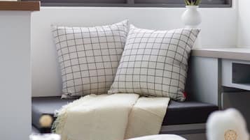 A modern room with a window seat featuring two checkered pillows and a white throw blanket.