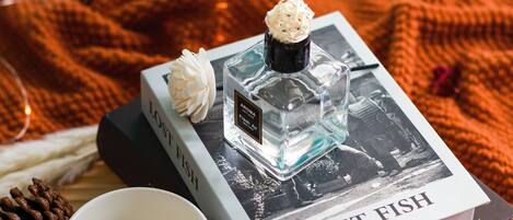 A book titled 'Lost Fish' with a perfume bottle on top, a white flower, and a white cup beside it.