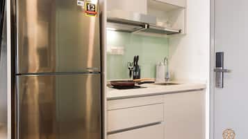 Una cocina moderna con un refrigerador de acero inoxidable, un microondas y un horno empotrado. Hay un lavamanos con grifo, una encimera con un bloque para cuchillos y un portavasos para copas de vino.
