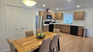 A modern kitchen with wooden cabinets, a stainless steel refrigerator, and a black dishwasher. - Eastern Desert Chic (Umatilla)