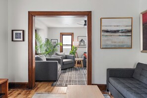 A modern living room with a grey sofa, a wooden coffee table, and a patterned rug. - NordEast Escape/Hot Tub, Bocce court, Fooseball, Patio, Awesome location (Minneapolis)