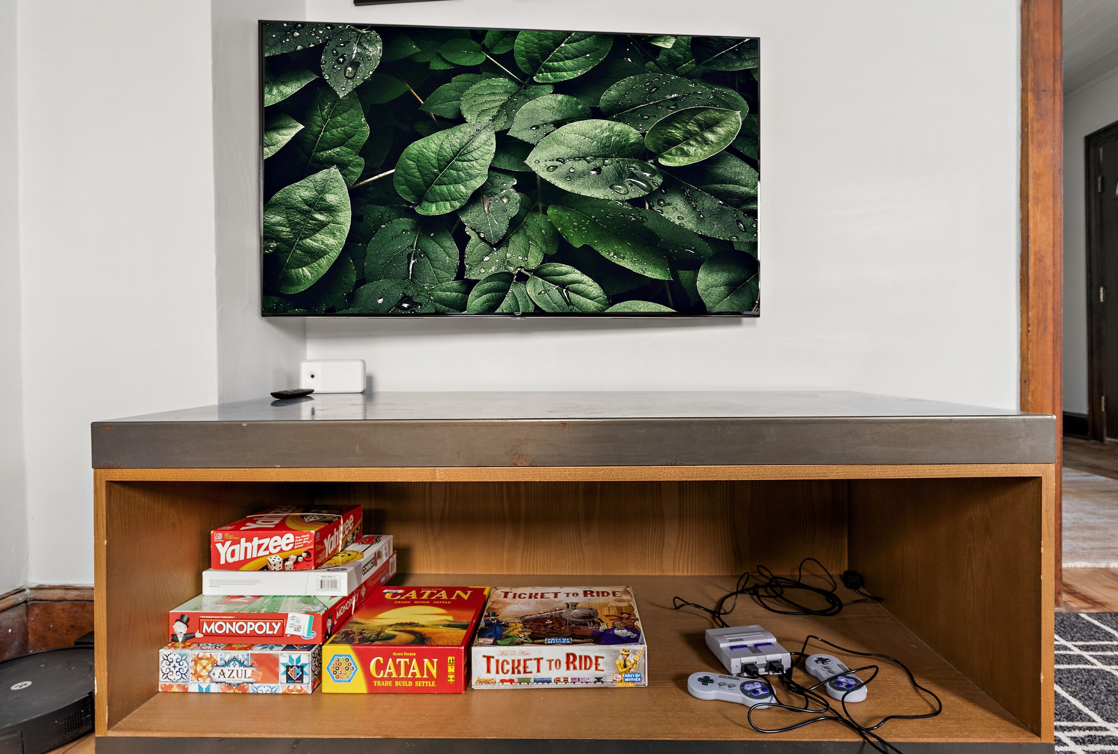 A wooden entertainment unit with board games and a television above it.