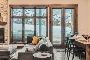 Un salon chaleureux avec une cheminée, un canapé, une table basse et un coin repas avec des chaises et une table mise pour le repas.