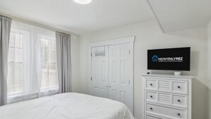 A bedroom with a bed, a dresser, a television, and a door.