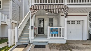 A two-story residential building with a front porch, a staircase, and a garage.