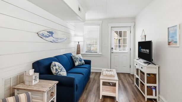 A living room with a blue sofa, a small wooden table, a TV, and a white door.