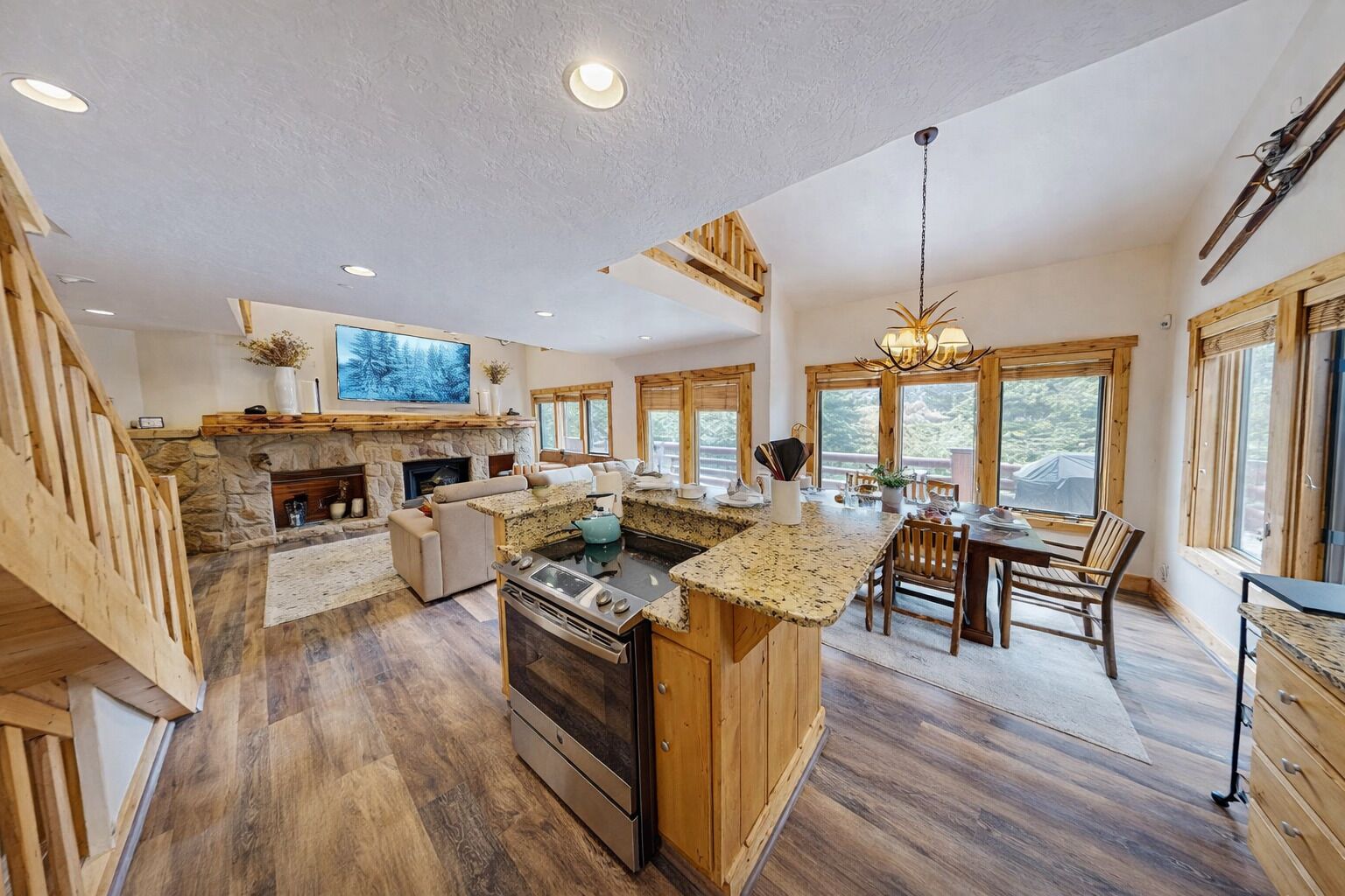 A spacious kitchen with a stone fireplace, wooden accents, and large windows.