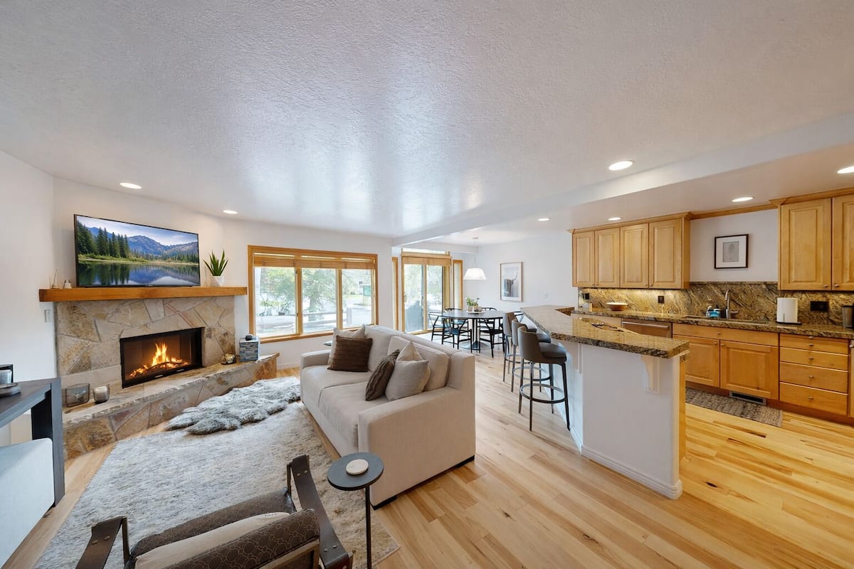 A modern open-plan living area with a fireplace, a sofa, and a dining area.