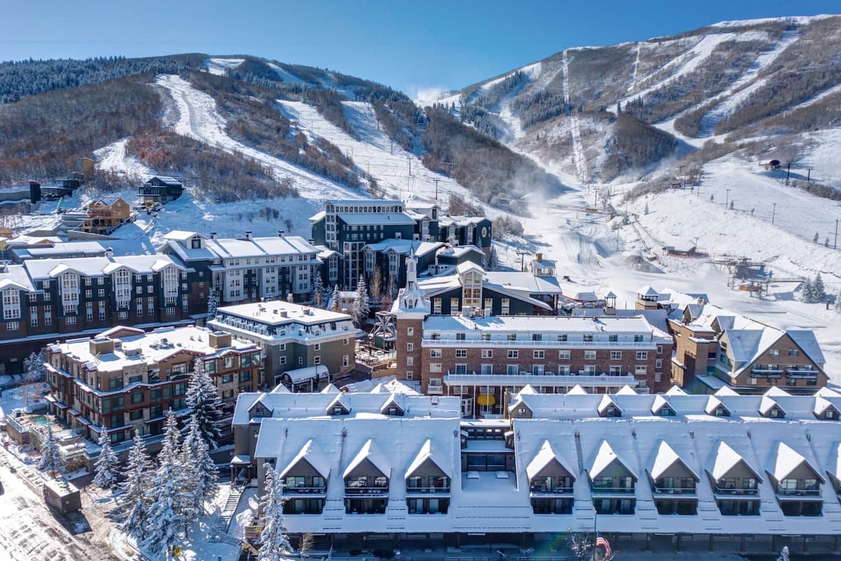 A snow-covered town with a mix of traditional and modern buildings, including a prominent hotel with a snow-covered roof and multiple stories.