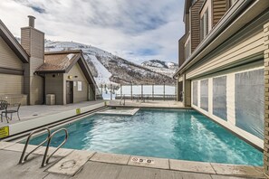 A swimming pool with a view of snow-covered mountains, a covered area with chairs, and a no diving sign. - Unique Park City Ski Resort Condos (Park City)