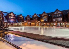 A hotel with a large outdoor ice skating rink, wooden buildings with dormer windows, and a well-lit facade. - Unique Park City Ski Resort Condos (Park City)