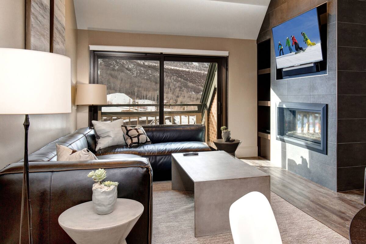 Ein modernes Wohnzimmer mit einer Ledersofa, einem Couchtisch und einem Kamin.
