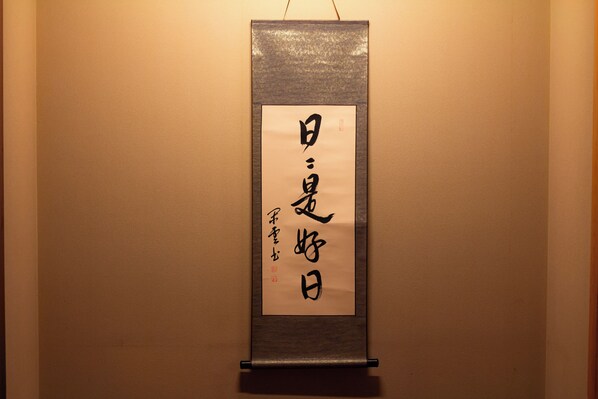 Een verticale rol met Japanse kalligrafie op een muur.