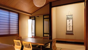 Ett traditionellt japanskt rum med tatamimattor på golvet, ett träbord och skjutdörrar.