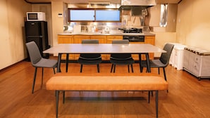 Een kleine keuken met een eethoek, houten kastjes, een magnetron en een spoelbak.