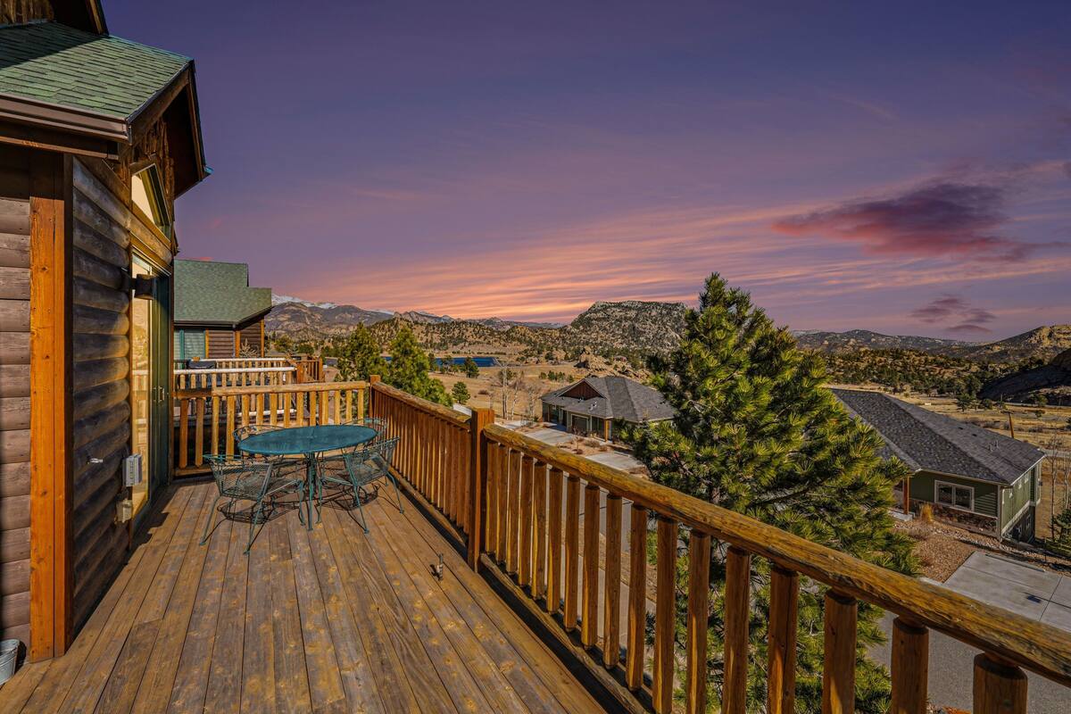Une terrasse en bois avec une table et des chaises, offrant une vue sur un paysage montagneux.
