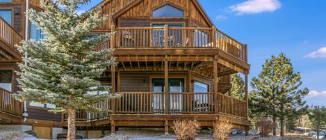 A wooden cabin with a balcony, surrounded by trees and snow.