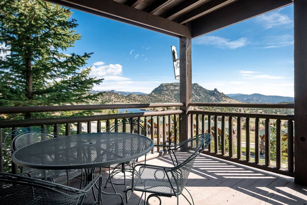 Un espace extérieur abrité, doté d’une table et de chaises, qui offre une vue sur un paysage montagneux.