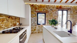 Eine Küche mit Stehwänden, einem Gasherd, einem Spülbecken und einem Fenster mit Blick.