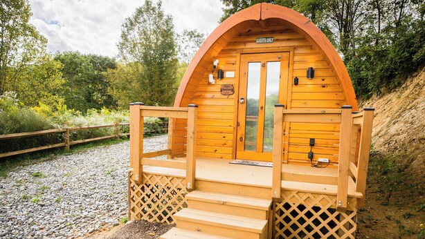 Une cabane en bois avec une pancarte indiquant « Réservé aux invités », une terrasse en bois et un escalier menant à l’entrée.