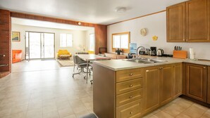 Une cuisine spacieuse dotée d’un grand îlot central, de meubles en bois et d’un coin repas avec une chaise jaune.
