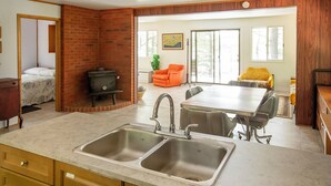 Une cuisine équipée d’un évier à deux bacs, de meubles en bois et d’un coin repas avec une table et des chaises.