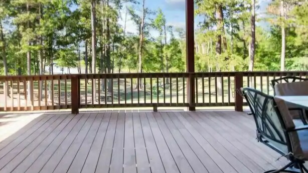 Une terrasse en bois avec un ventilateur de plafond, une table et des chaises, le tout installé sous une tonnelle.