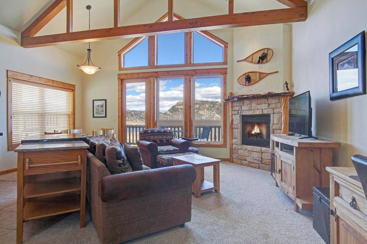 A spacious living room with a fireplace, large windows, a pool table, and a cozy seating area.