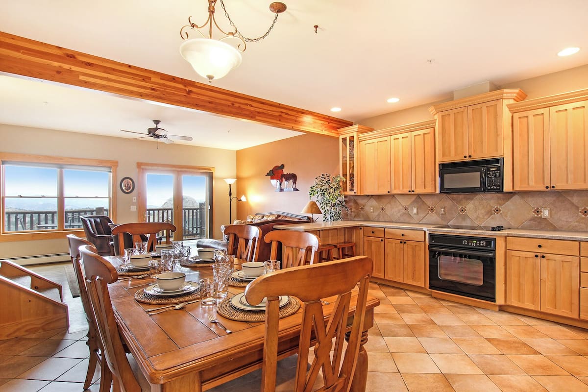 A spacious kitchen with wooden cabinets, a dining table set for six, and a view through the windows.