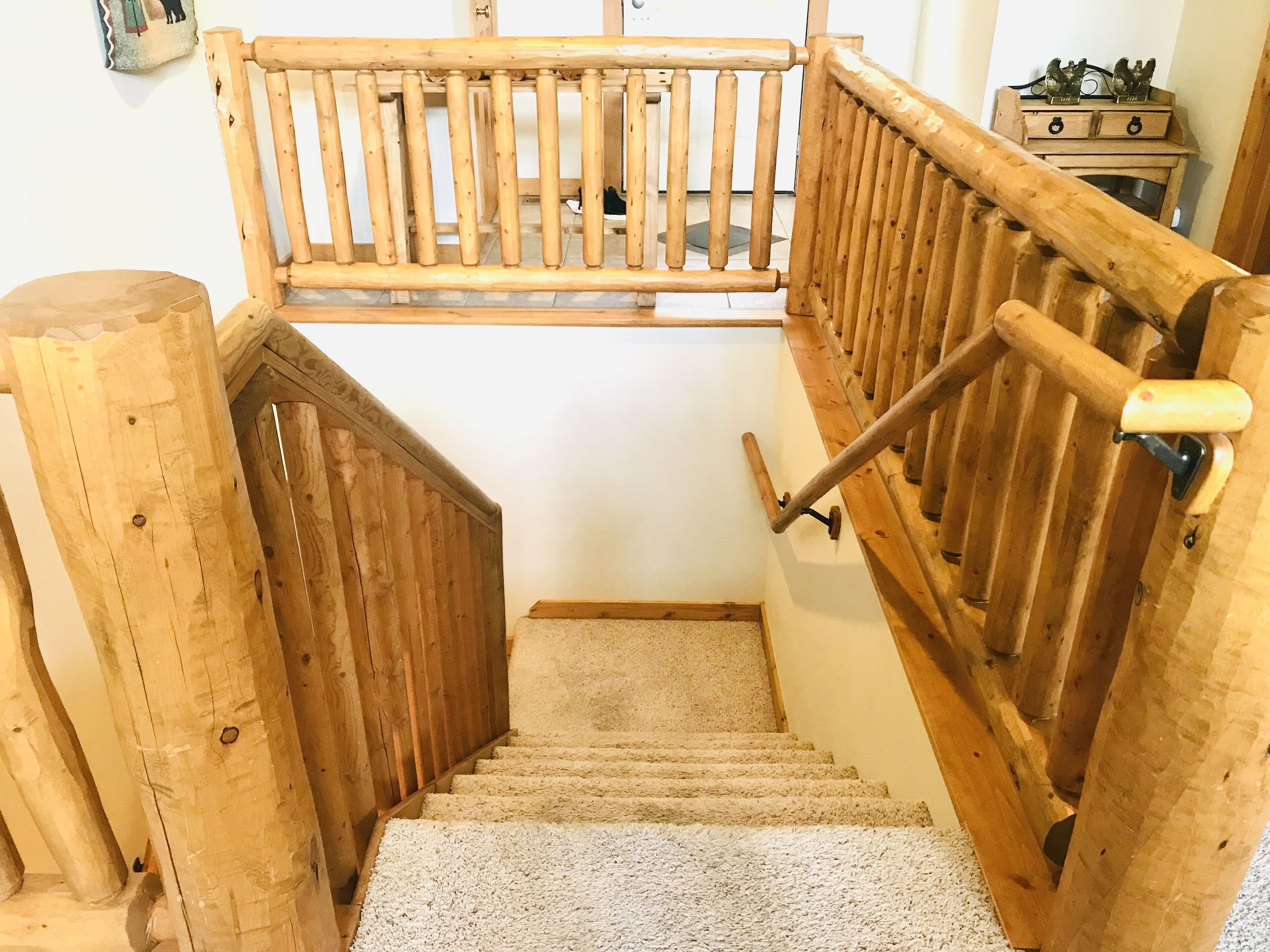Un escalier en bois, doté d’une rampe et d’un palier recouvert de moquette.