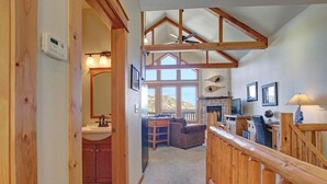 A spacious room with a wooden ceiling, a fireplace, a dining area, and a view of the outdoors. - Estes Park Vacation Lodging (Estes Park)