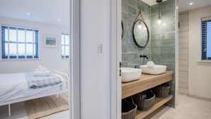 A modern bathroom with a large mirror, two sinks, and a wooden vanity.