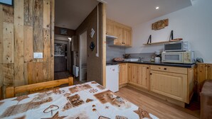 A compact kitchen with wooden cabinets, a microwave, and a refrigerator.