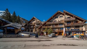 A multi-story hotel with balconies, a ski shop, and a sign for 'Acces Pistes'.