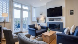 A modern living room with a fireplace, a flat-screen TV, and a view of the outside.