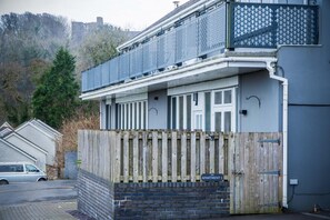 Ein zweistöckiges Wohnhaus mit Balkon, Holzpforte und einer Ziegelbasis.