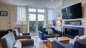 A modern living room with a fireplace, comfortable seating, and a large TV.