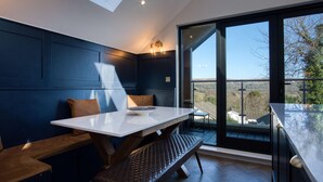 Un intérieur moderne comprenant un coin repas, un banc et une vue sur l’extérieur.