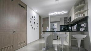 Una cocina moderna con una isla central, taburetes de bar y un reloj en la pared.