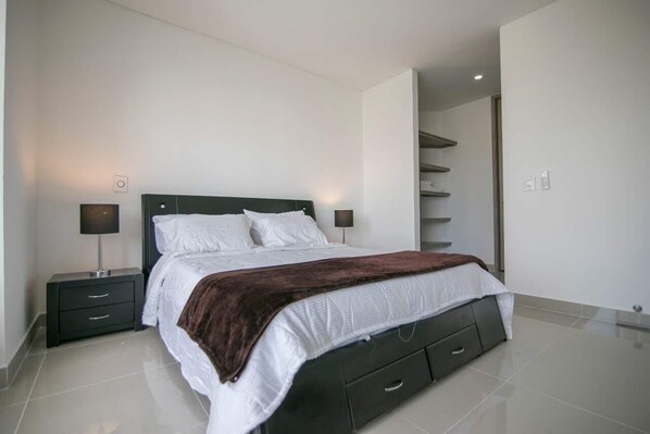 Une chambre à coucher moderne avec un lit, des tables de chevet et une bibliothèque intégrée.