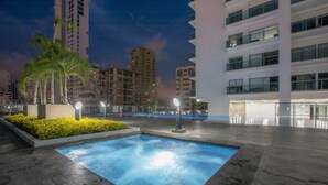 Zona de piscina con pileta rectangular, rodeada por un deck empedrado y palmeras.