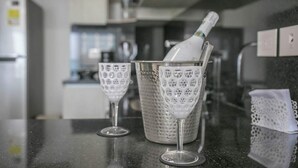 Una encimera de cocina con una botella de champán en un cubo de vidrio, dos copas de vino y un paño blanco.