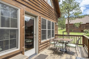 A wooden cabin with a deck, large windows, and outdoor furniture. - Cozy Solitude Cabins - Estes Park CO (Estes Park)