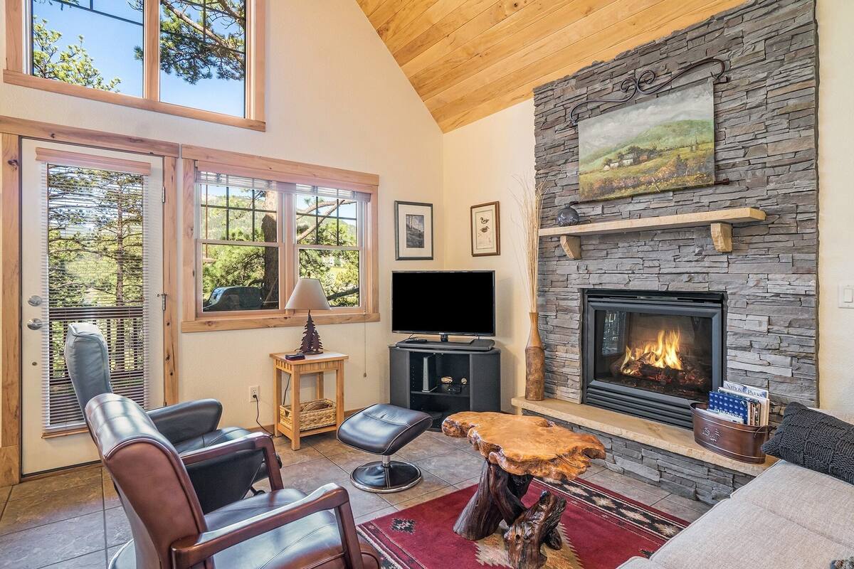 A cozy living room with a stone fireplace, a television, and comfortable seating.