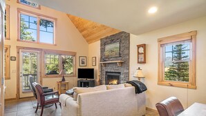 A cozy living room with a fireplace, a sofa, a television, and a dining table.